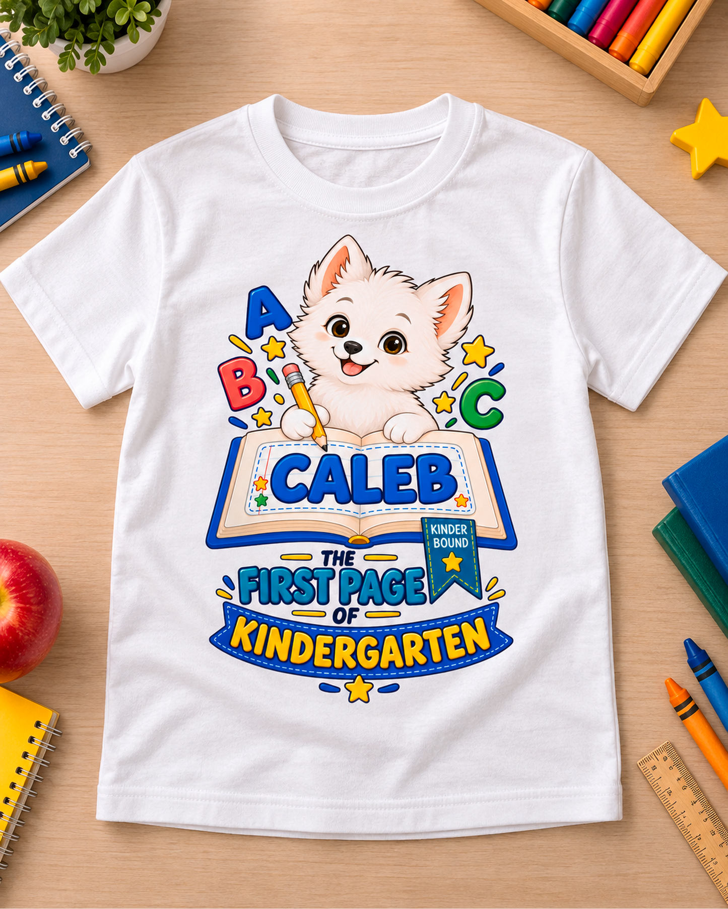 White personalized kindergarten ABC dog youth shirt flat lay with the sample name Caleb.