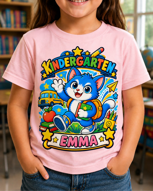 Child wearing a light pink personalized kindergarten cat shirt with the example name Emma in a classroom.
