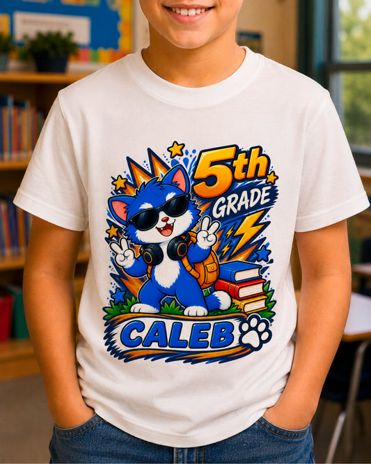 Child wearing a white personalized fifth grade cool cat shirt with the sample name Caleb in a classroom.