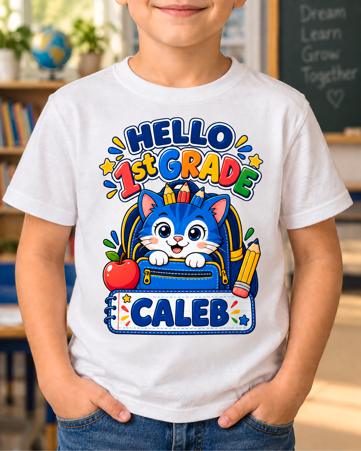 Child wearing a white personalized first grade backpack cat shirt with the sample name Caleb in a classroom.