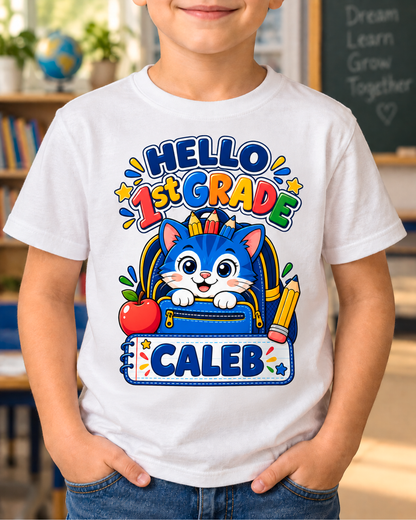 Child wearing a white personalized first grade backpack cat shirt with the sample name Caleb in a classroom.