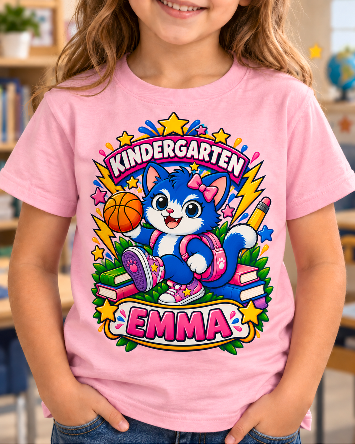 Child wearing a light pink personalized kindergarten basketball cat shirt with the sample name Emma in a classroom.