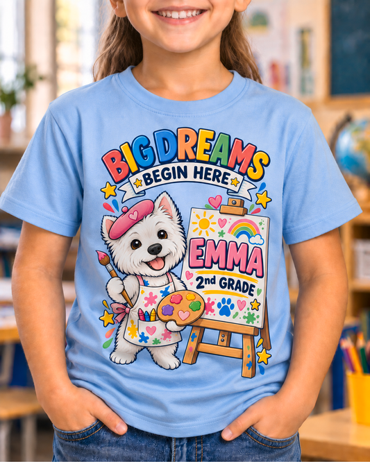Child wearing a light blue personalized second grade artist dog shirt with the sample name Emma in a classroom.