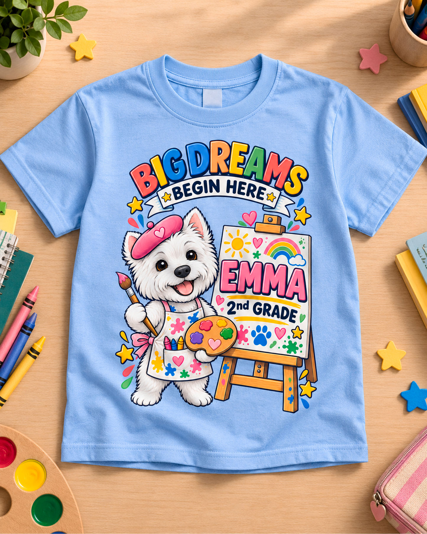 Light blue personalized second grade artist dog youth shirt flat lay with the sample name Emma.