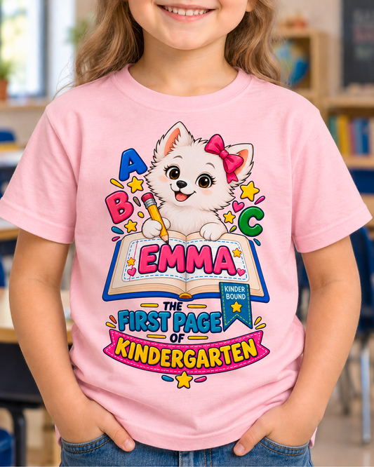 Child wearing a light pink personalized kindergarten ABC dog shirt with the sample name Emma in a classroom.