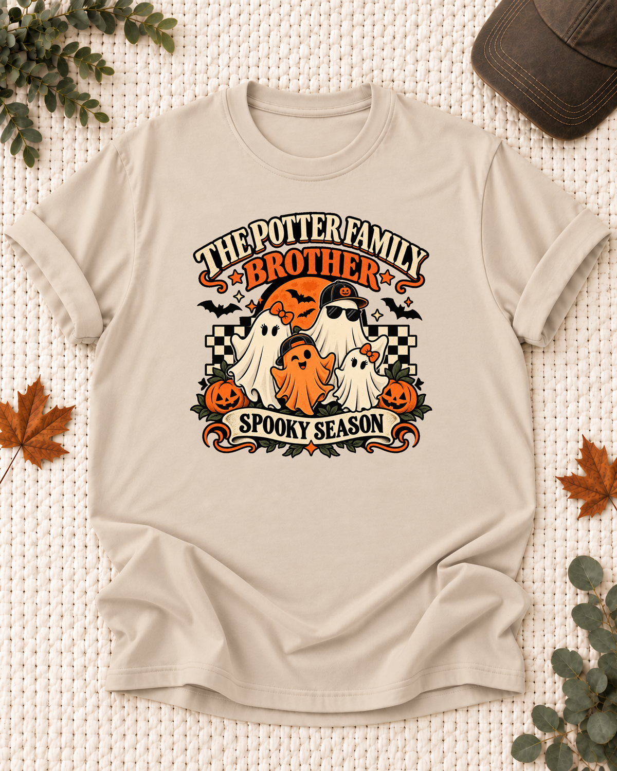 Sand Brother T-shirt with four friendly ghosts, jack-o'-lanterns, bats, an orange moon, black-and-cream checkerboard accents, and example family-name text.
