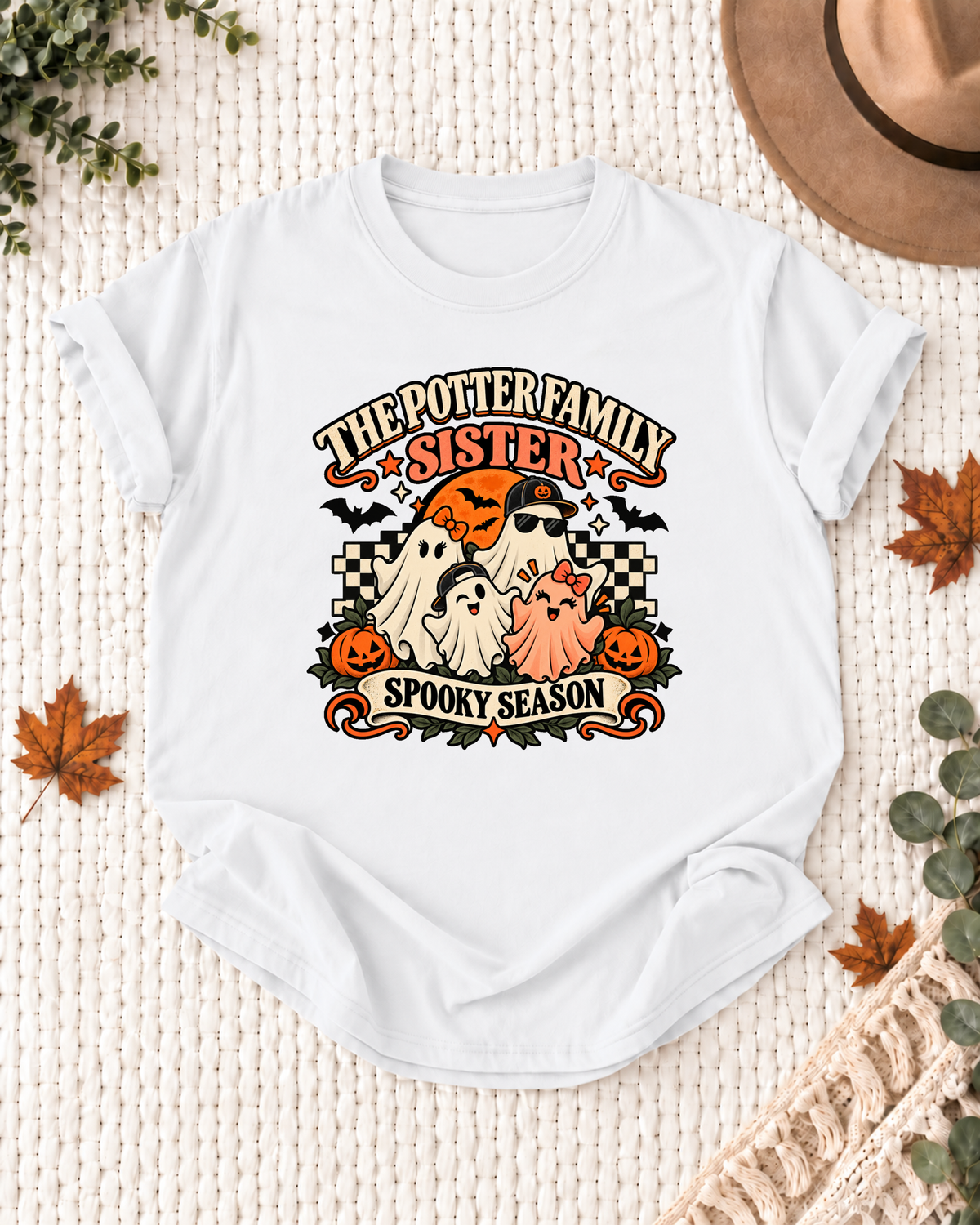 White Sister T-shirt with four friendly ghosts, jack-o'-lanterns, bats, an orange moon, black-and-cream checkerboard accents, and example family-name text.
