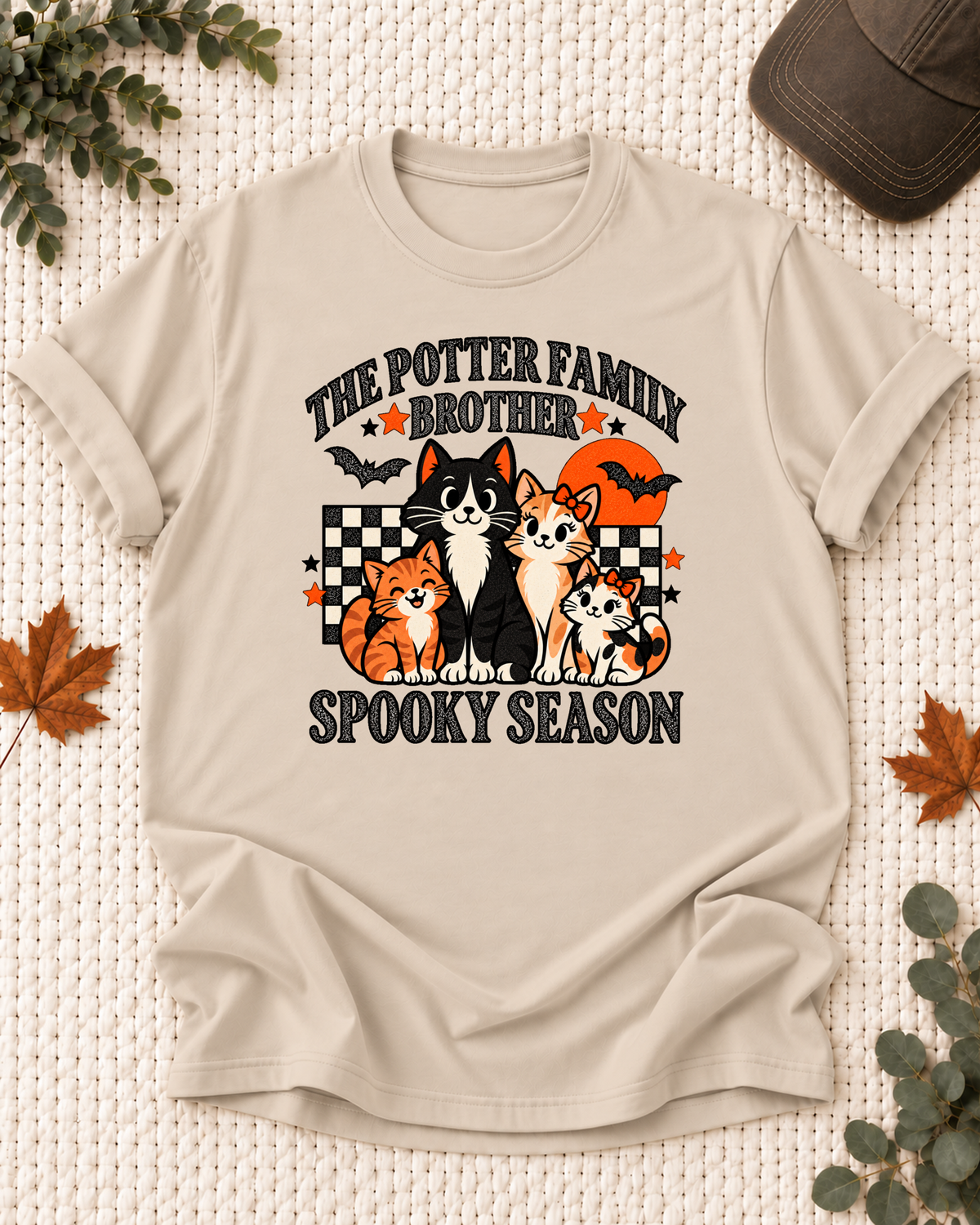 Sand Brother T-shirt with four illustrated cats, an orange moon, bats, black-and-cream checkerboard accents, jack-o'-lanterns, and example family-name text.