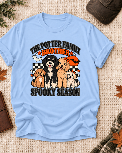 Light blue Brother T-shirt with four illustrated dogs, an orange moon, bats, black-and-cream checkerboard accents, and example family-name text.