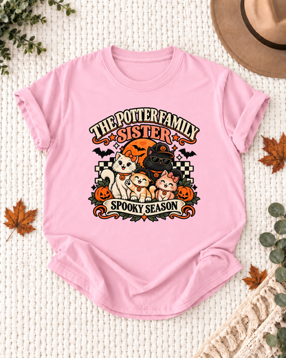 Light pink Sister T-shirt with costume-inspired cats, including a black cat in a pumpkin cap and sunglasses, with example family-name text.
