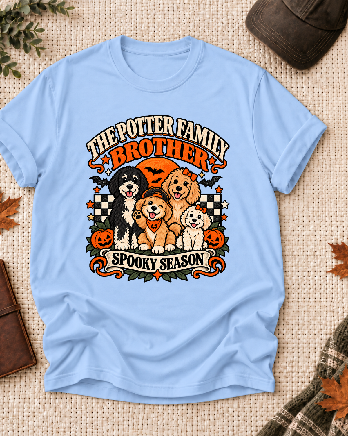 Light blue Brother T-shirt with orange role lettering, four dogs, jack-o'-lanterns, and "Spooky Season" text, showing the example name "The Potter Family."
