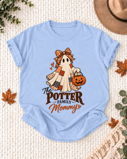 Light blue Mommy T-shirt with a patchwork ghost wearing a bow and scarf, holding a jack-o'-lantern, with example family-name text.