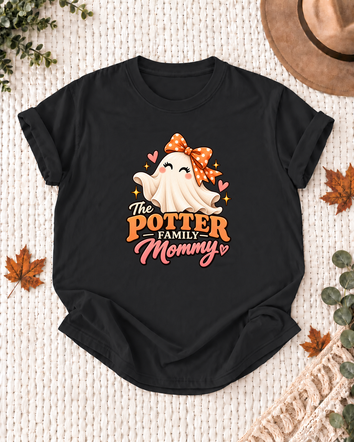 Mommy's Black personalized Halloween shirt mockup with a smiling ghost with an orange polka-dot bow and heart accents, sample family lettering, and the role label.