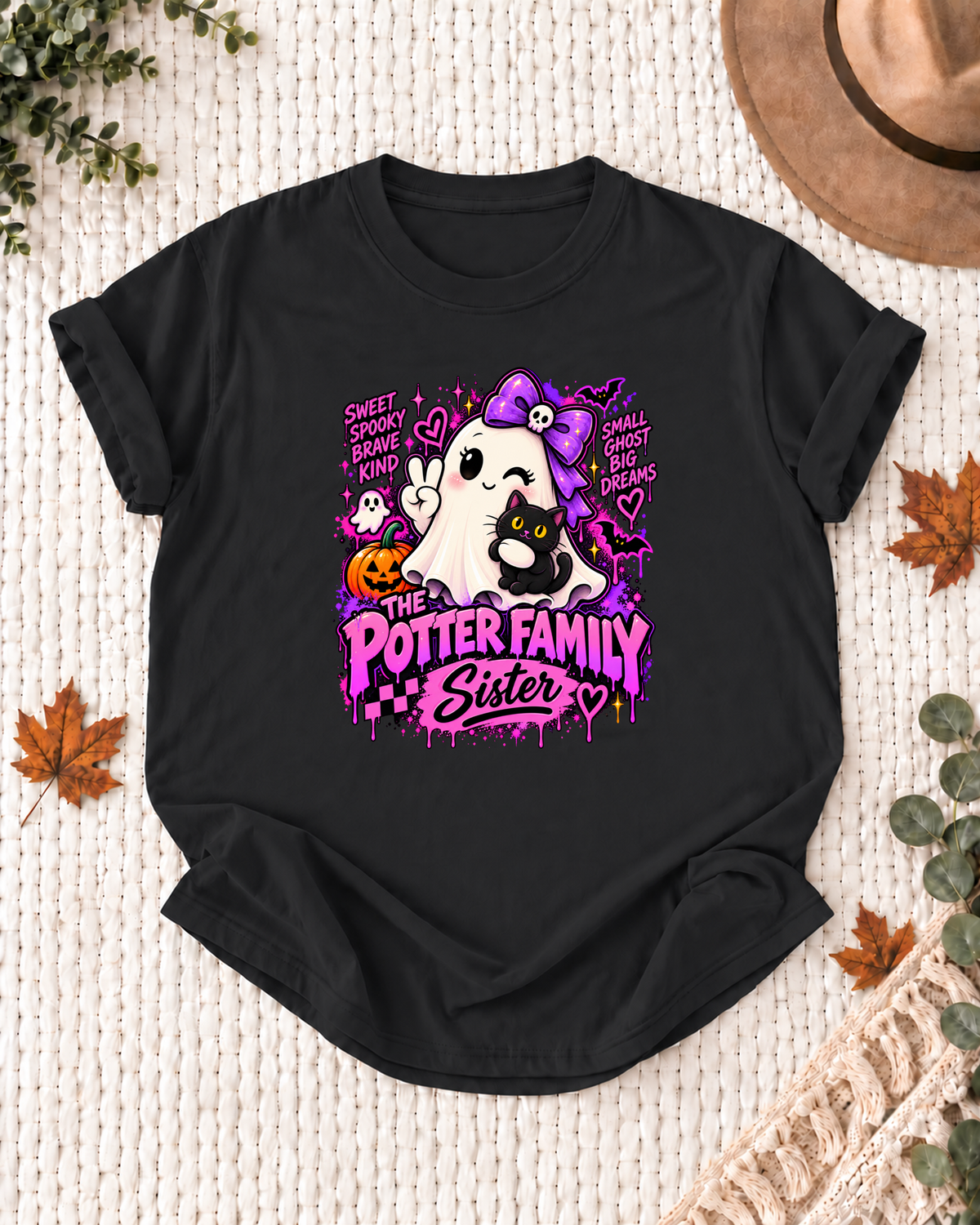 Sister's Black personalized Halloween shirt mockup with a ghost with a purple bow, black cat, pumpkin, and pink accents, sample family lettering, and the role label.