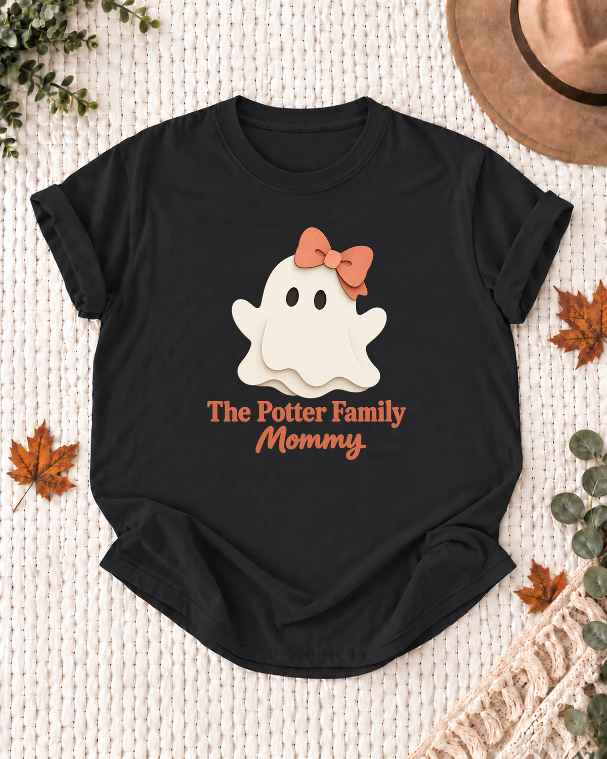 Mommy's Black personalized Halloween shirt mockup with a minimal cream ghost with a peach bow, sample family lettering, and the role label.
