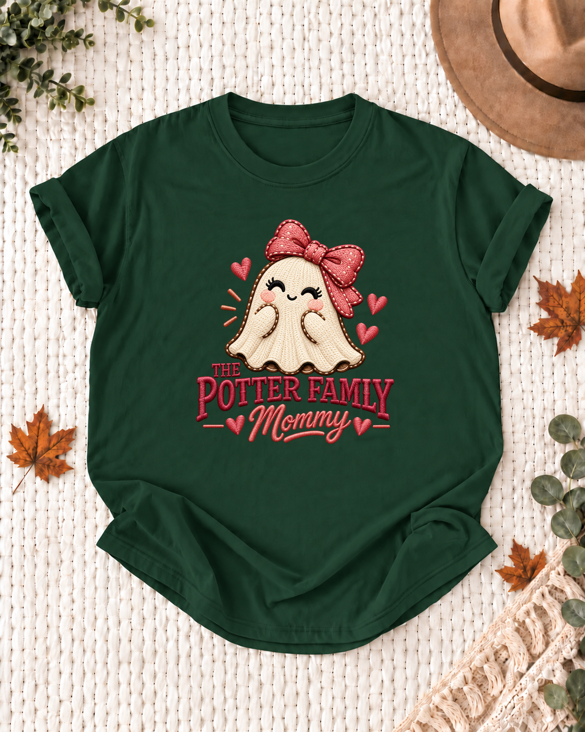 Mommy's Dark Green personalized Halloween shirt mockup with a stitched-look ghost with a red bow and hearts, sample family lettering, and the role label.