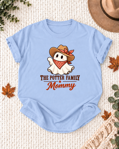 Mommy's Light Blue personalized Halloween shirt mockup with a ghost with a brown cowboy hat, red bandana, and floral bow, sample family lettering, and the role label.