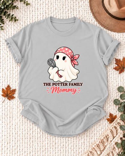 Mommy's Ash Grey personalized Halloween shirt mockup with a baking ghost with a chef hat and whisk, sample family lettering, and the role label.