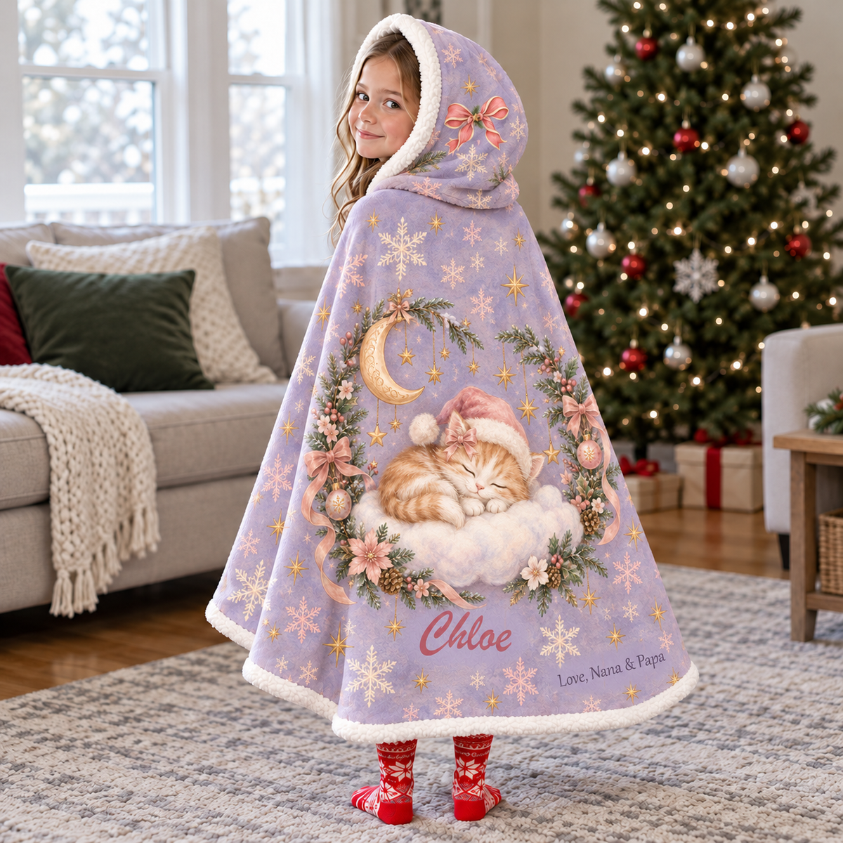 Child wearing a lavender hooded blanket with a sleeping Christmas kitten, cloud, moon, and stars, plus example name Chloe and signature Love, Nana & Papa.